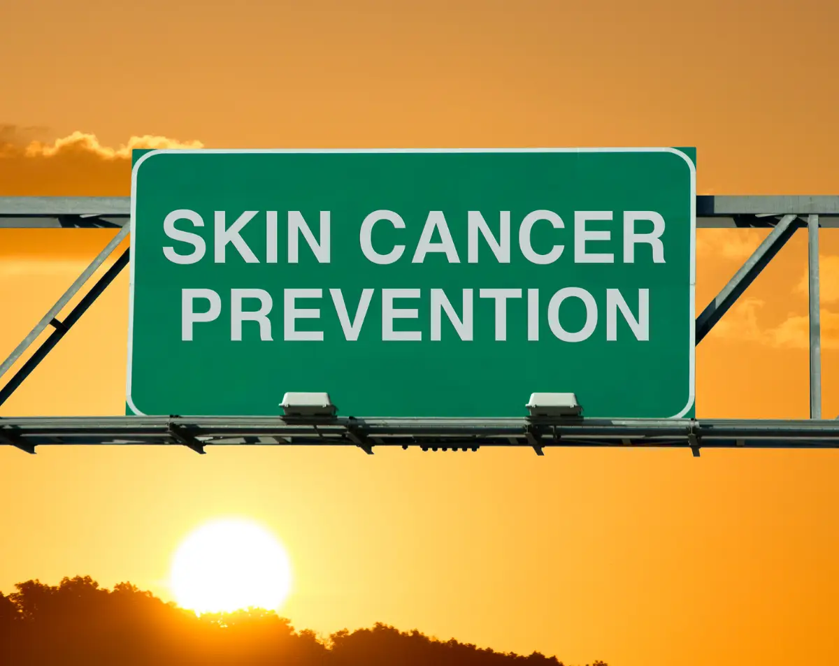 Skin cancer prevention road sign with sunset background, emphasizing the importance of skin health and awareness.