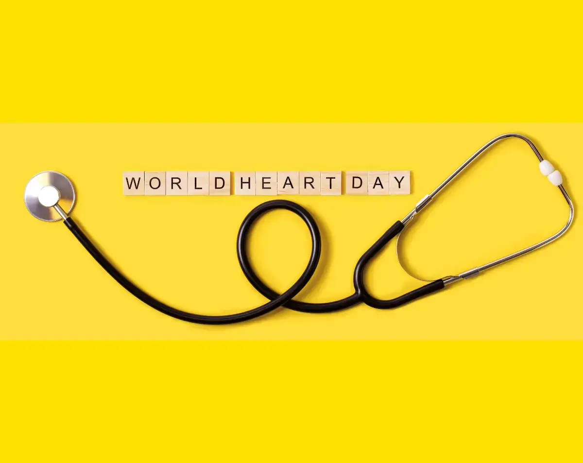 Stethoscope on yellow background with letter blocks spelling "WORLD HEART DAY," symbolizing heart health awareness.