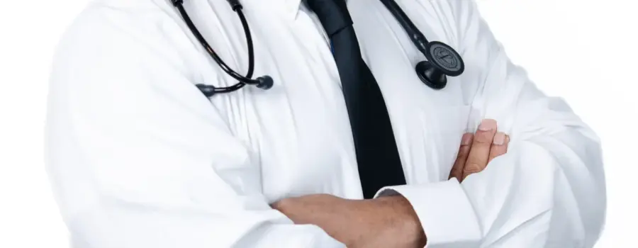 Male doctor in a white shirt and tie, smiling with arms crossed.